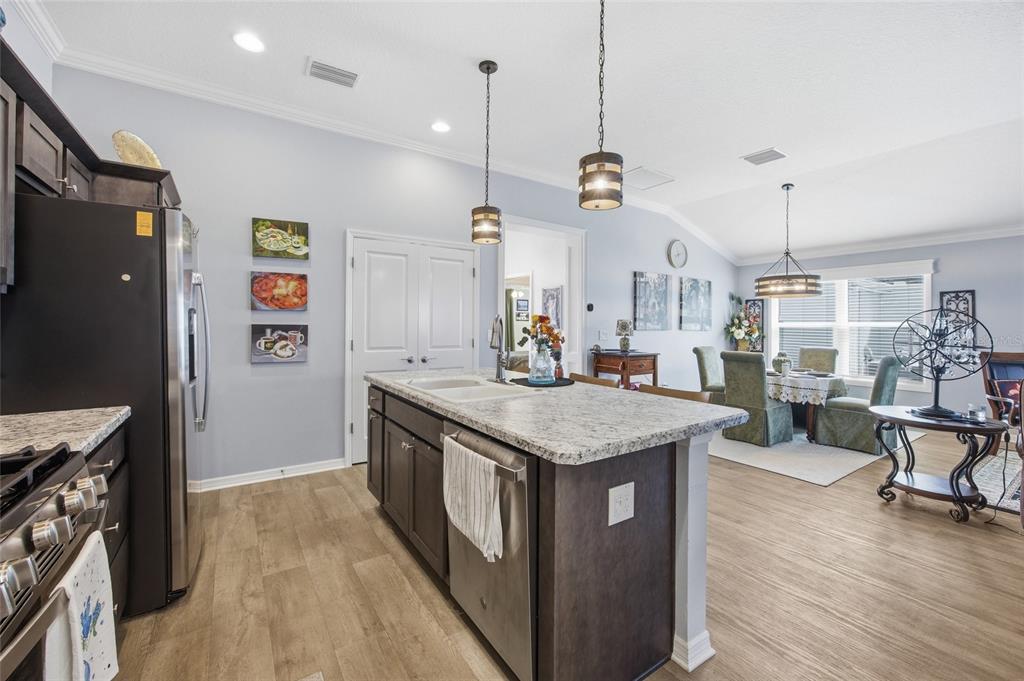 A kitchen with dark cabinets, granite countertops, and an island opens to a dining area — 2910 MONUMENT WAY, THE VILLAGES, FL