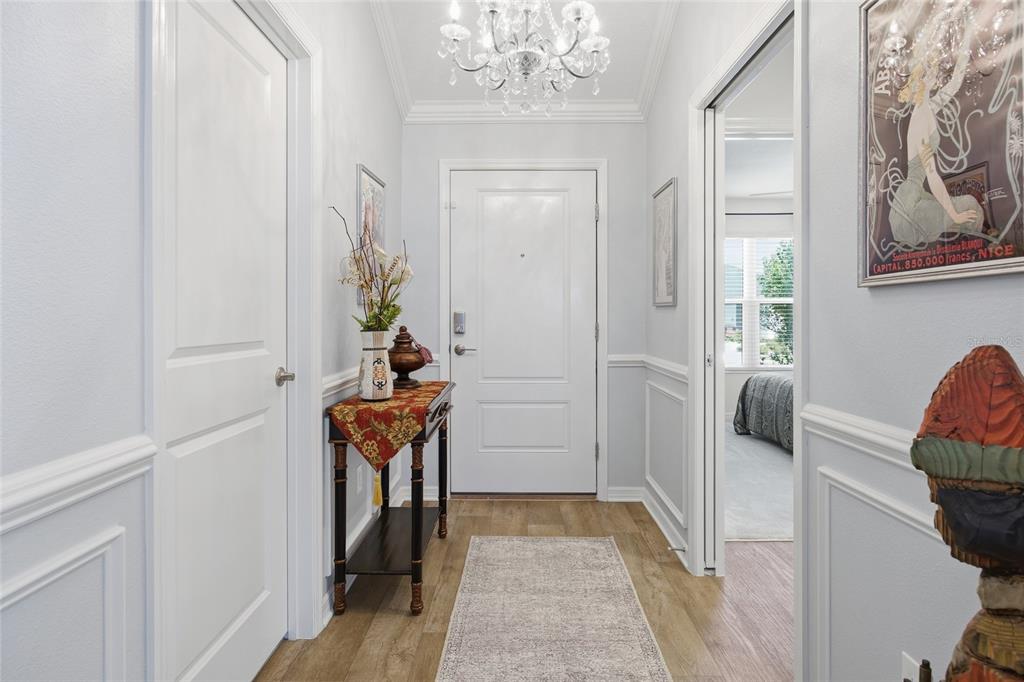 A bright entryway features light blue walls, white wainscoting, a chandelier, and a wood-look floor — 2910 MONUMENT WAY, THE VILLAGES, FL