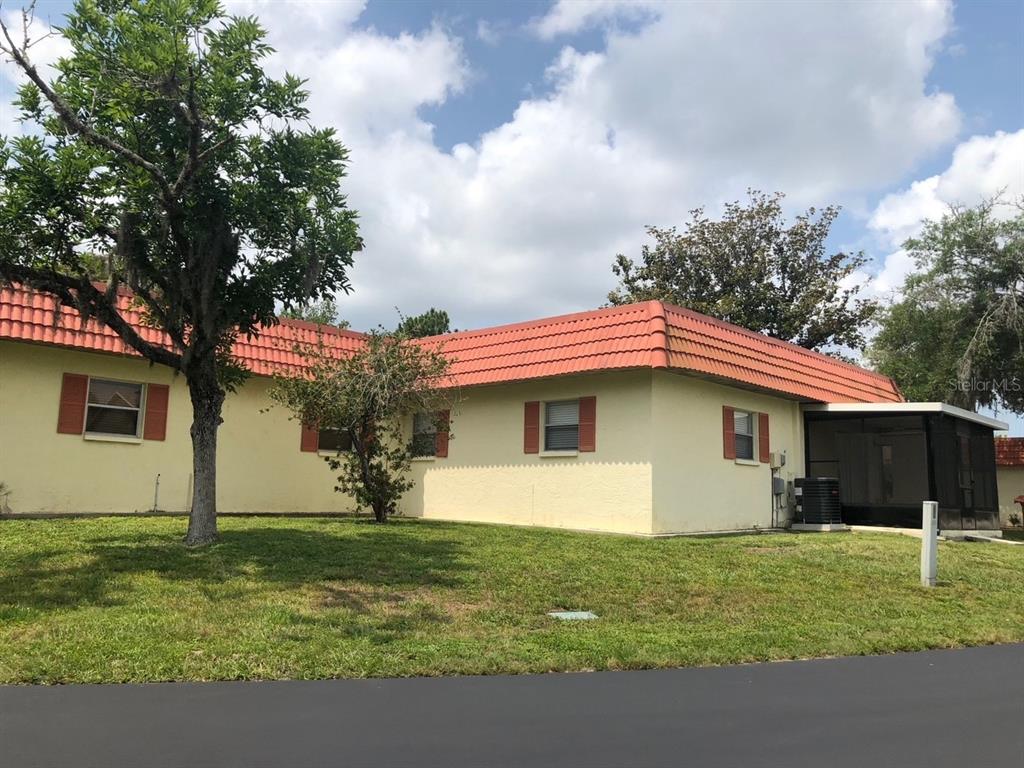 A single-story house with a red tile roof, yellow stucco walls, and a screened-in porch — 4008 EL MERITA COURT, NEW PORT RICHEY, FL