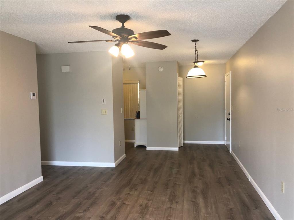 An open living area features wood-look flooring, a ceiling fan, and a hanging pendant light — 4008 EL MERITA COURT, NEW PORT RICHEY, FL