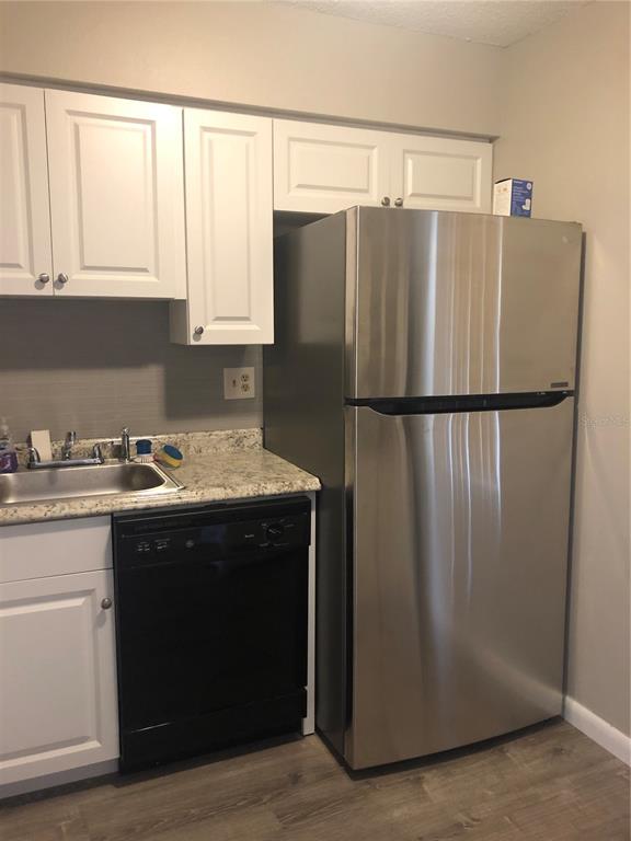 A kitchen features white cabinets, a stainless steel refrigerator, a black dishwasher, and granite countertops — 4008 EL MERITA COURT, NEW PORT RICHEY, FL