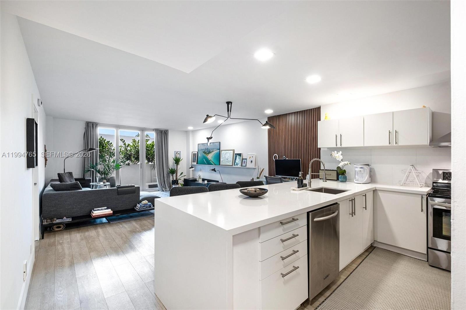 A modern, open-concept kitchen with white cabinetry and an island overlooks a living area — 5 Island Ave, Miami Beach FL 33139, MIAMI BEACH, FL