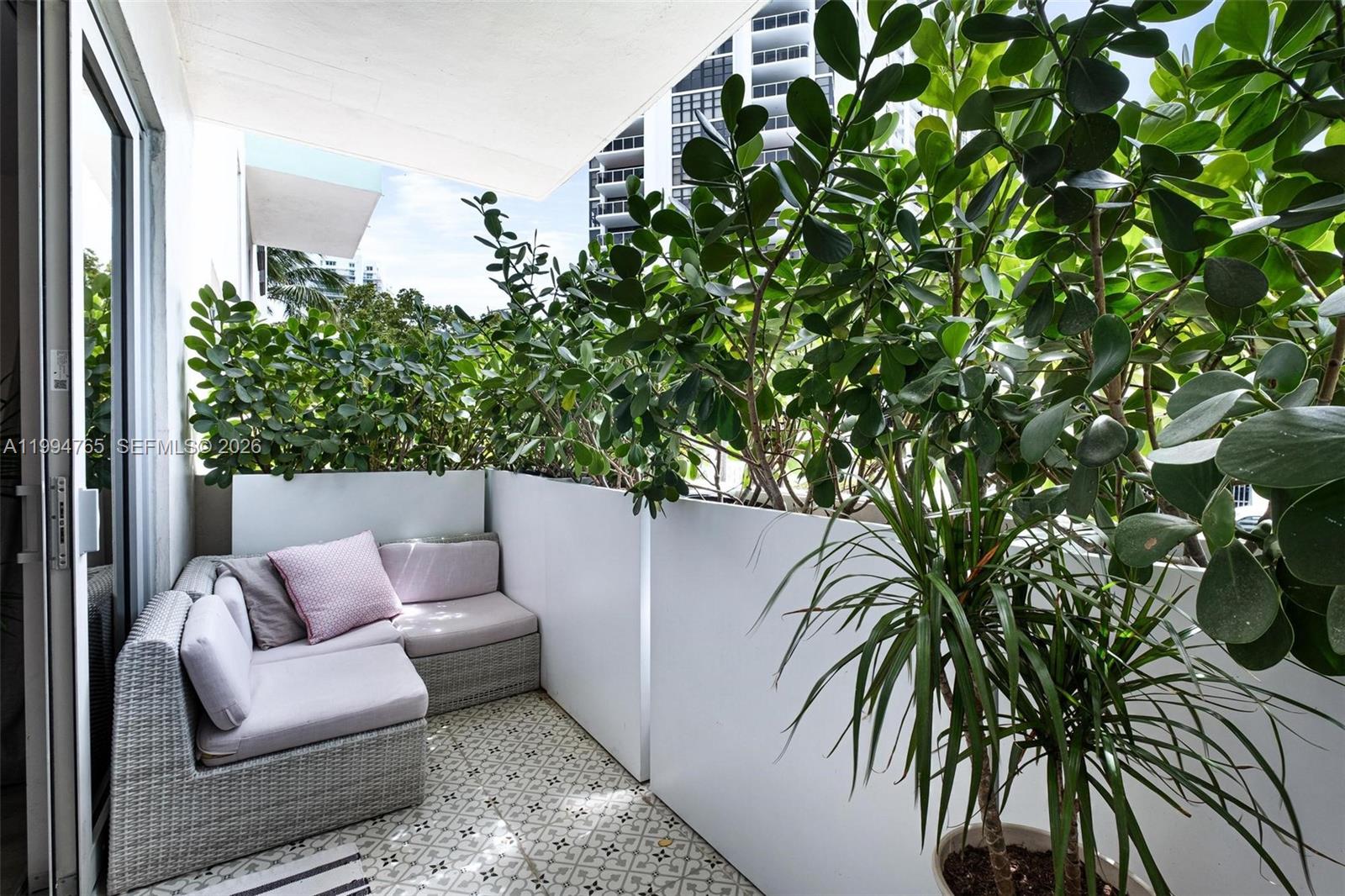 A balcony features a gray sectional sofa, patterned tile flooring, and tall privacy planters — 5 Island Ave, Miami Beach FL 33139, MIAMI BEACH, FL