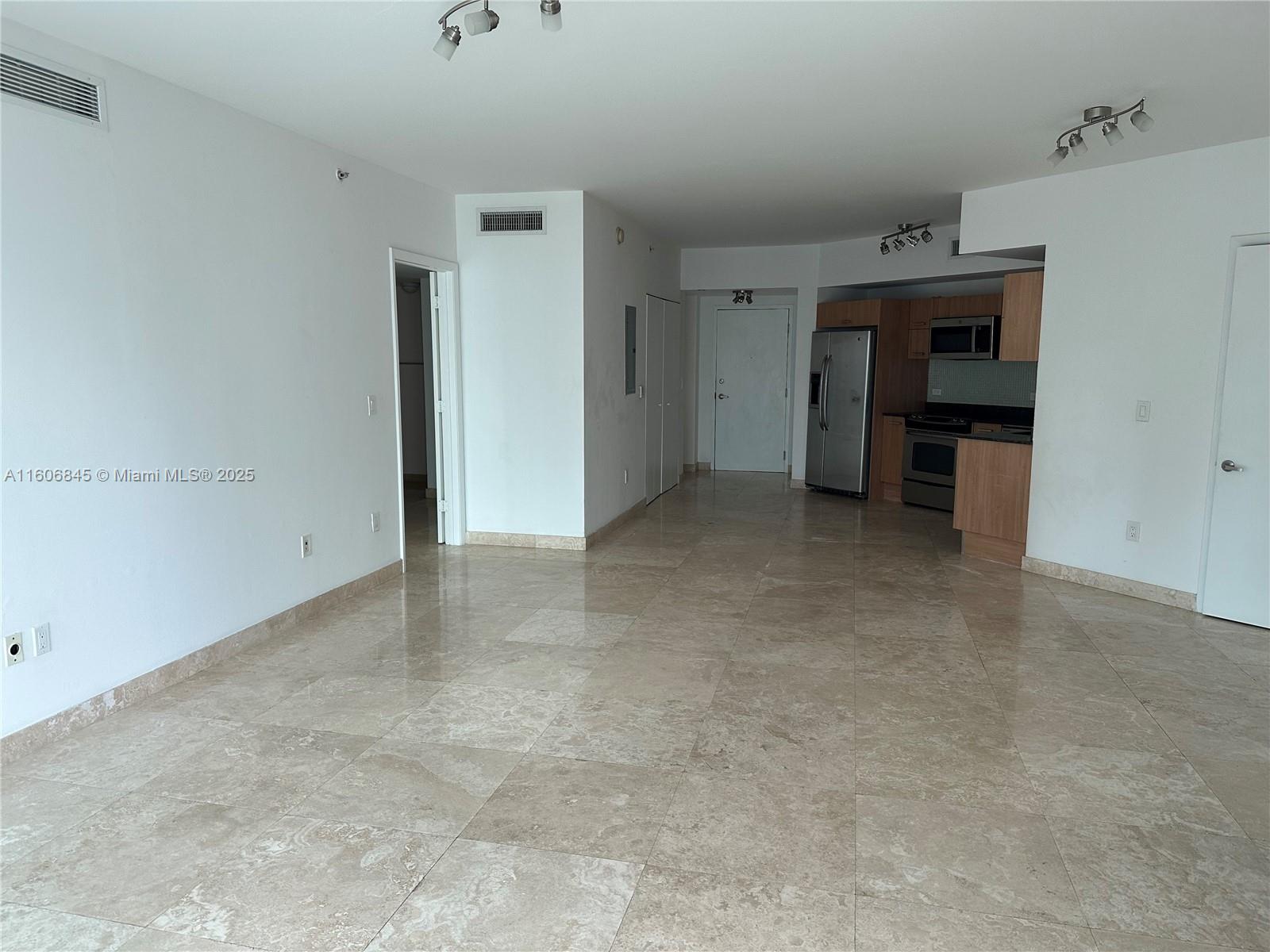An open-concept living area features light-colored tile flooring, white walls, and an adjacent kitchen — 350 S Miami Ave # 2302, Miami FL 33130, MIAMI, FL