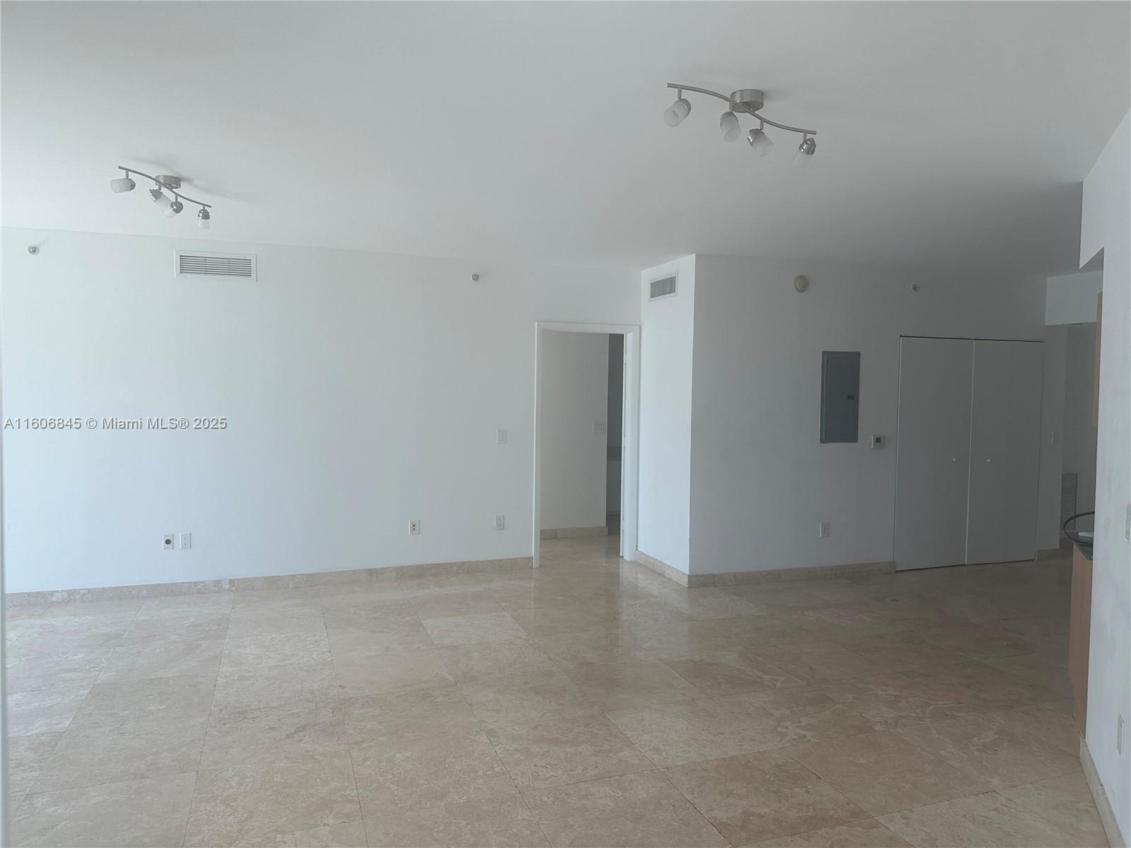 An empty room features white walls, tile flooring, two ceiling light fixtures, and a doorway — 350 S Miami Ave # 2302, Miami FL 33130, MIAMI, FL