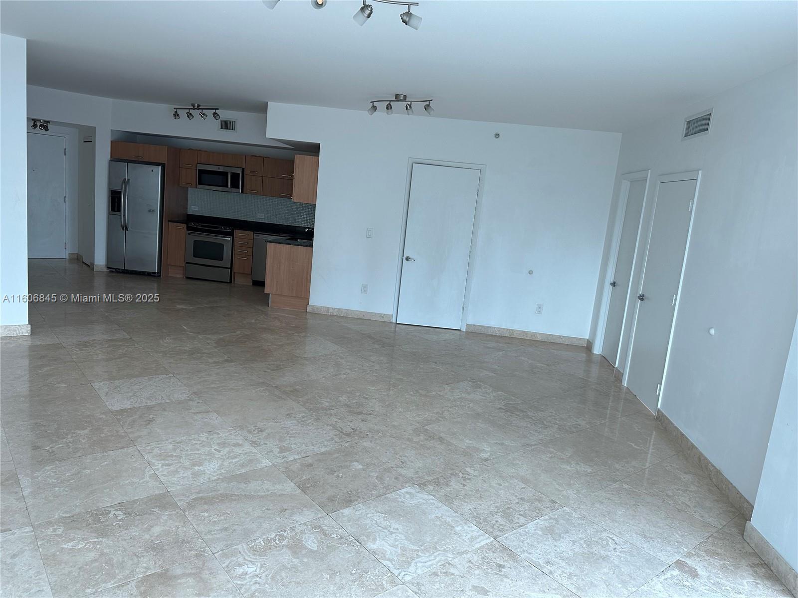 An open-concept living area features light-colored tile flooring and an adjacent kitchen with wood cabinetry — 350 S Miami Ave # 2302, Miami FL 33130, MIAMI, FL