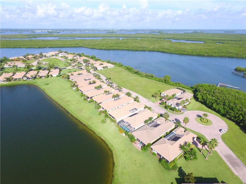 An aerial view shows a residential community with townhouses situated along a lake and mangroves — HUTCHINSON ISLAND, FL