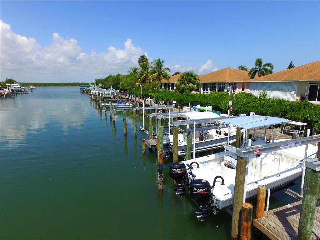 A row of boats is docked along a canal next to waterfront houses and palm trees — HUTCHINSON ISLAND, FL