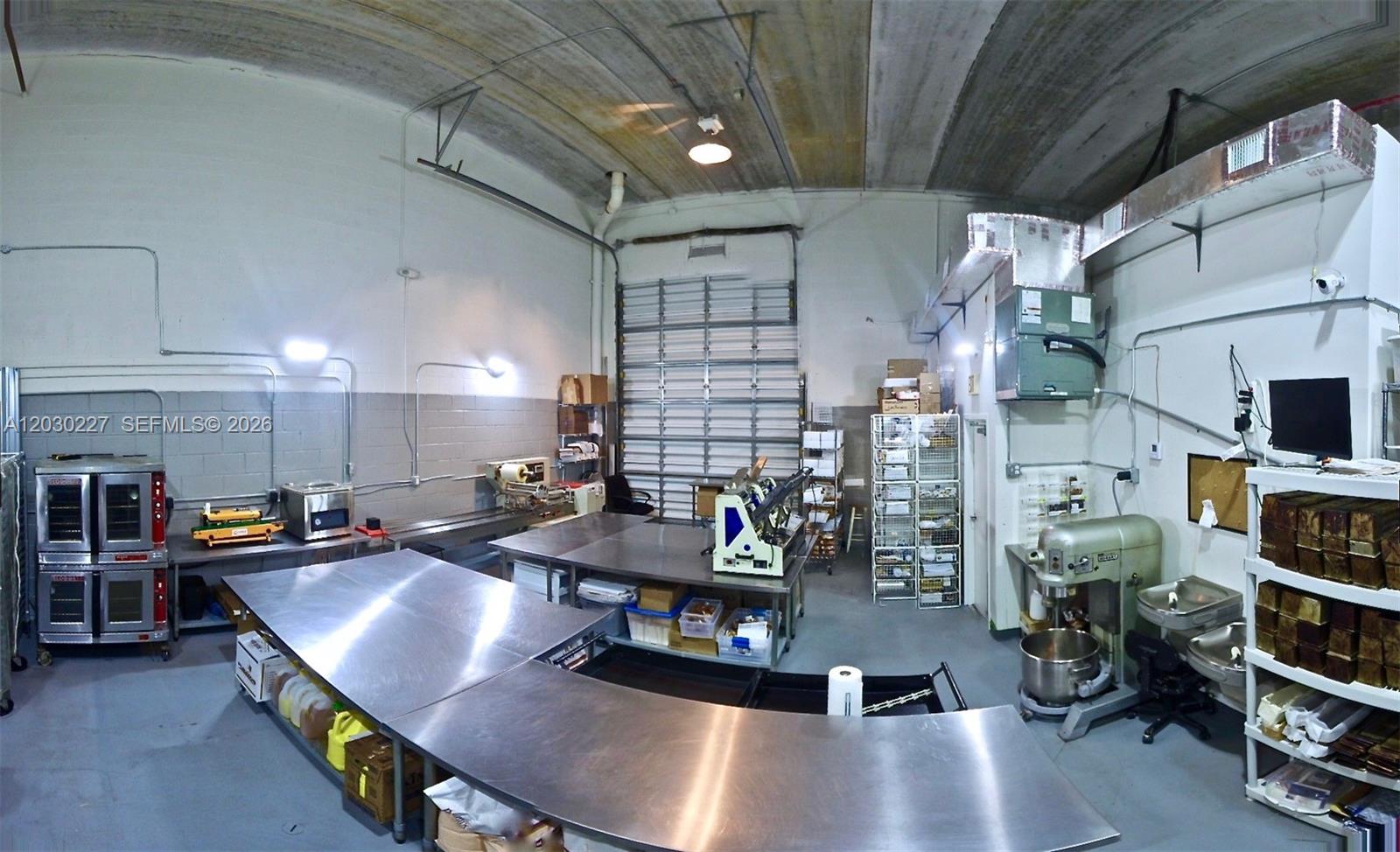 A commercial kitchen space features stainless steel work tables, industrial ovens, and a large mixer — 1365 NW 98th Ct, Doral FL 33172, DORAL, FL