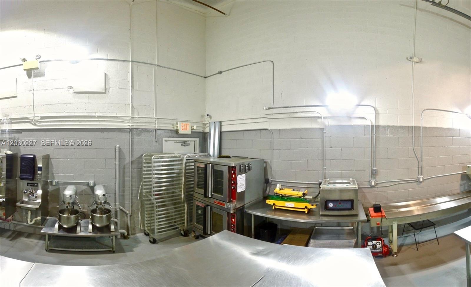 A commercial kitchen features stainless steel prep tables, industrial mixers, a double oven, and shelving — 1365 NW 98th Ct, Doral FL 33172, DORAL, FL