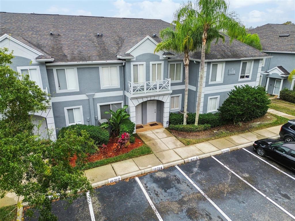 An exterior view of a two-story gray apartment building with a parking lot in front — 18214 PARADISE POINT DRIVE, TAMPA, FL
