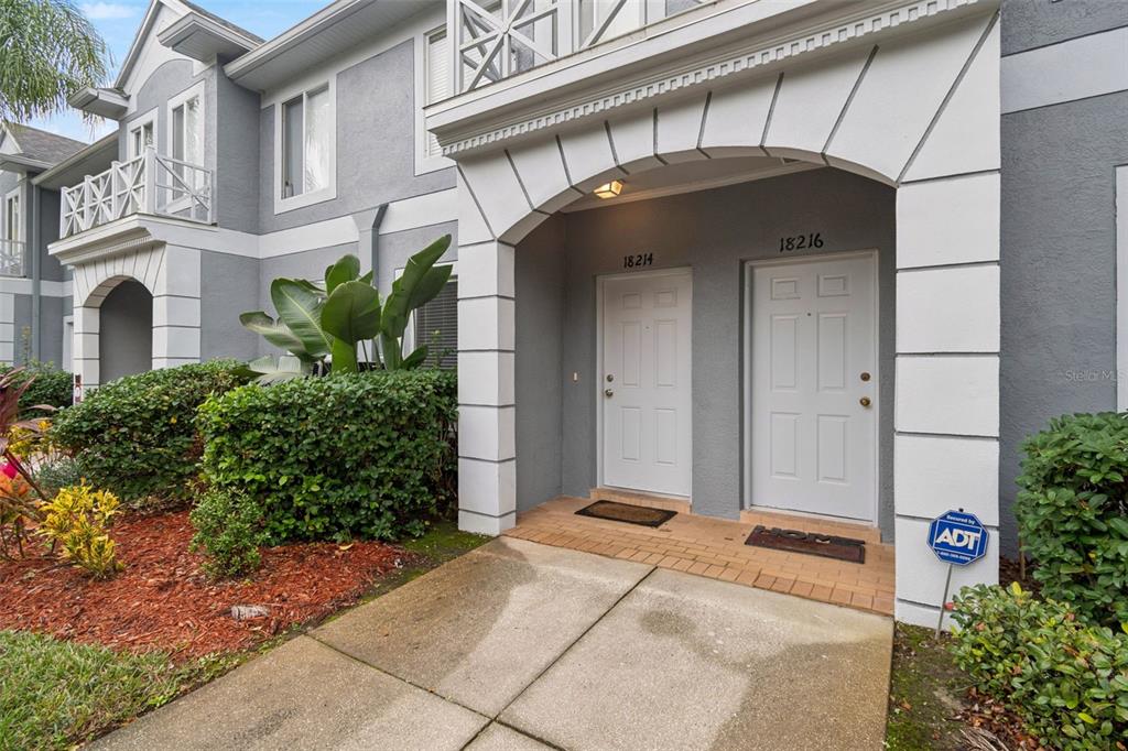The exterior of a two-story gray building features two white front doors under an archway — 18214 PARADISE POINT DRIVE, TAMPA, FL