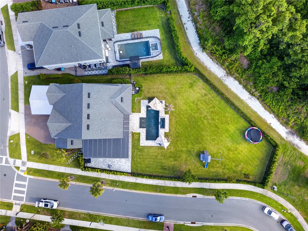Aerial view of two suburban houses with swimming pools and backyards along a curved street — 14406 HAROCHE AVENUE, ORLANDO, FL