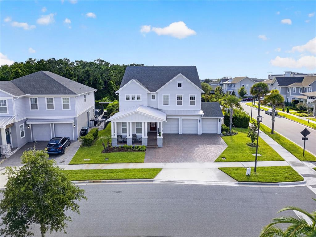 A two-story light blue house with a front porch and a three-car garage — 14406 HAROCHE AVENUE, ORLANDO, FL