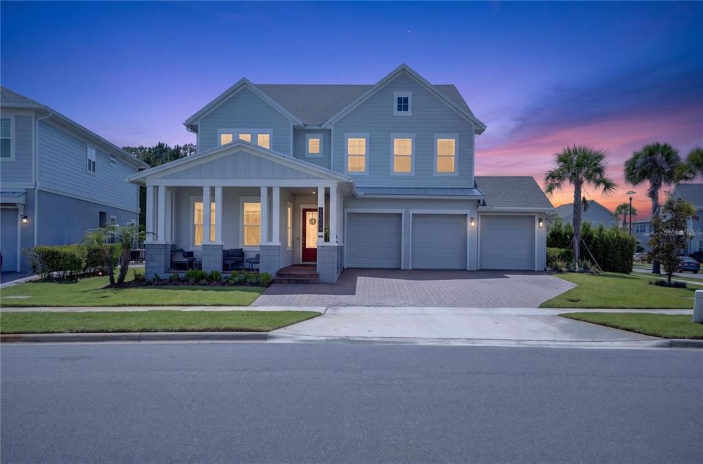 A two-story house with a front porch, three garage bays, and a paved driveway — 14406 HAROCHE AVENUE, ORLANDO, FL