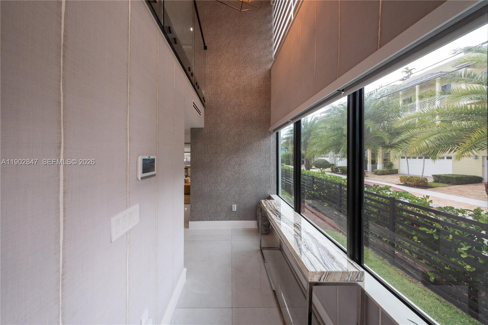 A modern hallway features a marble-topped console table, floor-to-ceiling windows, and textured wall coverings — 5601 N Ocean Dr, Hollywood FL 33019, HOLLYWOOD, FL