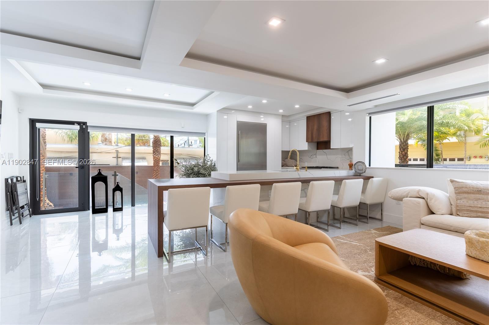 A modern open-concept kitchen and living area features white cabinetry, a wood-topped island, and tile floors — 5601 N Ocean Dr, Hollywood FL 33019, HOLLYWOOD, FL