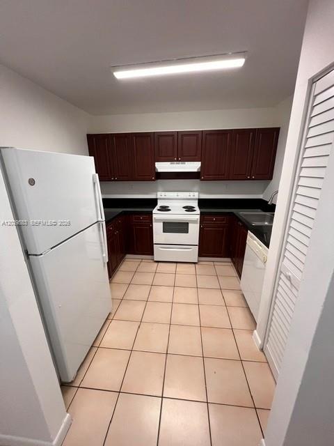 A kitchen features white appliances, dark wood cabinets, and light-colored floor tiles — 2690 W 76th St # 106, Hialeah FL 33016, HIALEAH, FL