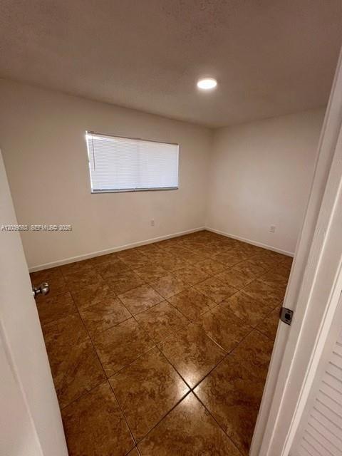 An empty bedroom features brown tile flooring, white walls, and a single window with blinds — 2690 W 76th St # 106, Hialeah FL 33016, HIALEAH, FL