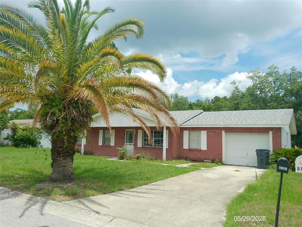 A single-story red brick house with a palm tree in the front yard — 6131 DOE CIRCLE E, LAKELAND, FL