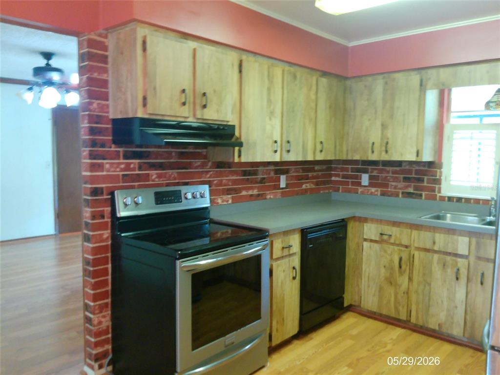 A kitchen features wood cabinets, a brick backsplash, and black appliances — 6131 DOE CIRCLE E, LAKELAND, FL