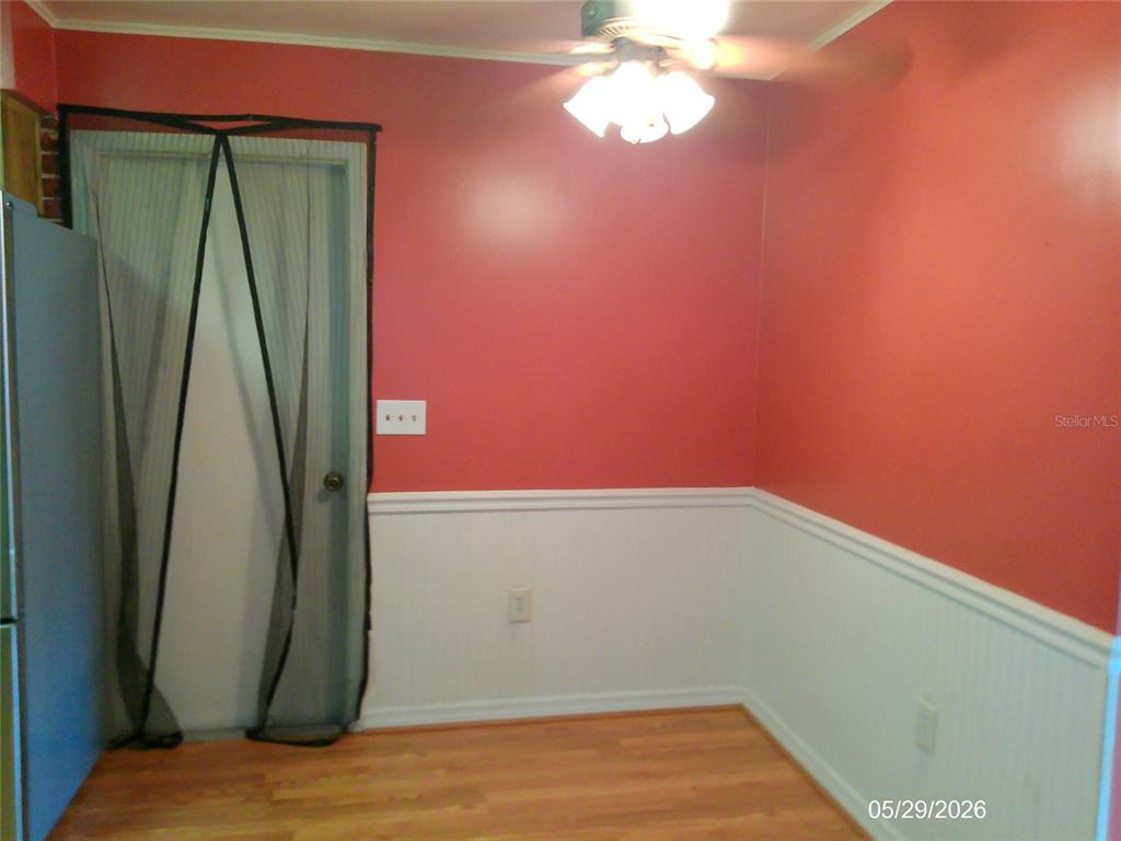 A dining area features red walls, white wainscoting, wood-look flooring, and a ceiling fan — 6131 DOE CIRCLE E, LAKELAND, FL