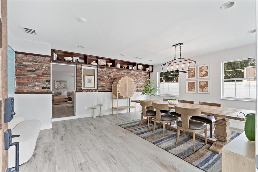 A dining room features a long wooden table, exposed brick wall, and built-in shelving — 3601 W DALE AVENUE, TAMPA, FL