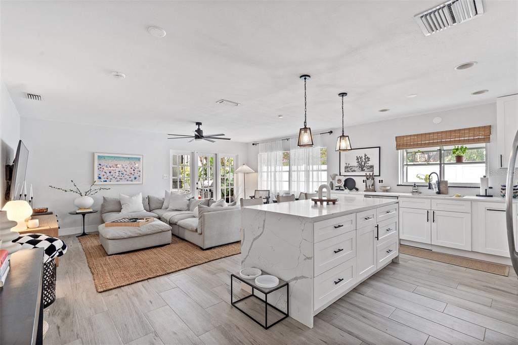 A bright open-concept kitchen and living area features a marble island and light wood flooring — 3601 W DALE AVENUE, TAMPA, FL