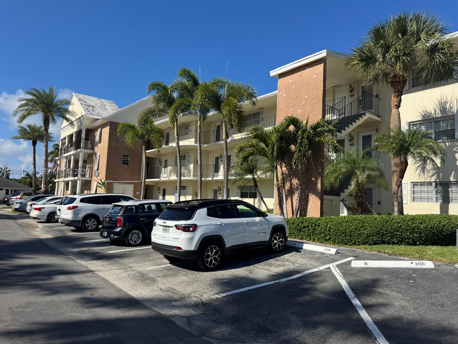 A white Jeep is parked in front of a multi-story apartment building with palm trees — 450 Paradise Isle Blvd # 209, Hallandale Beach FL 33009, HALLANDALE BEACH, FL