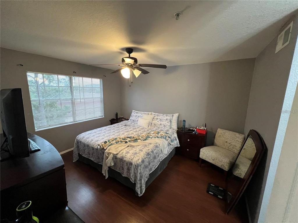 A bedroom features wood-look flooring, a ceiling fan, a bed, and a window with blinds — 13941 FAIRWAY ISLAND DRIVE UNIT 733, ORLANDO, FL