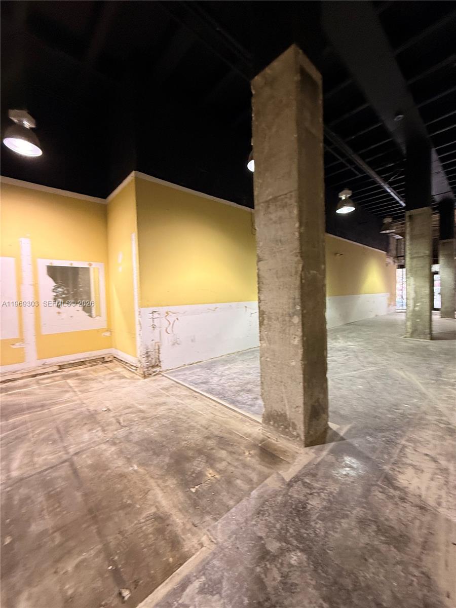 An unfinished commercial space features exposed concrete columns, yellow walls, and a dark ceiling — 28 W Flagler St # 102, Miami FL 33130, MIAMI, FL