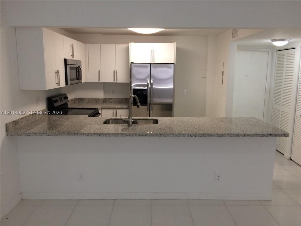 A kitchen features white cabinets, stainless steel appliances, and a granite countertop breakfast bar — 9143 SW 77 AV # B107, Miami FL 33156, MIAMI, FL