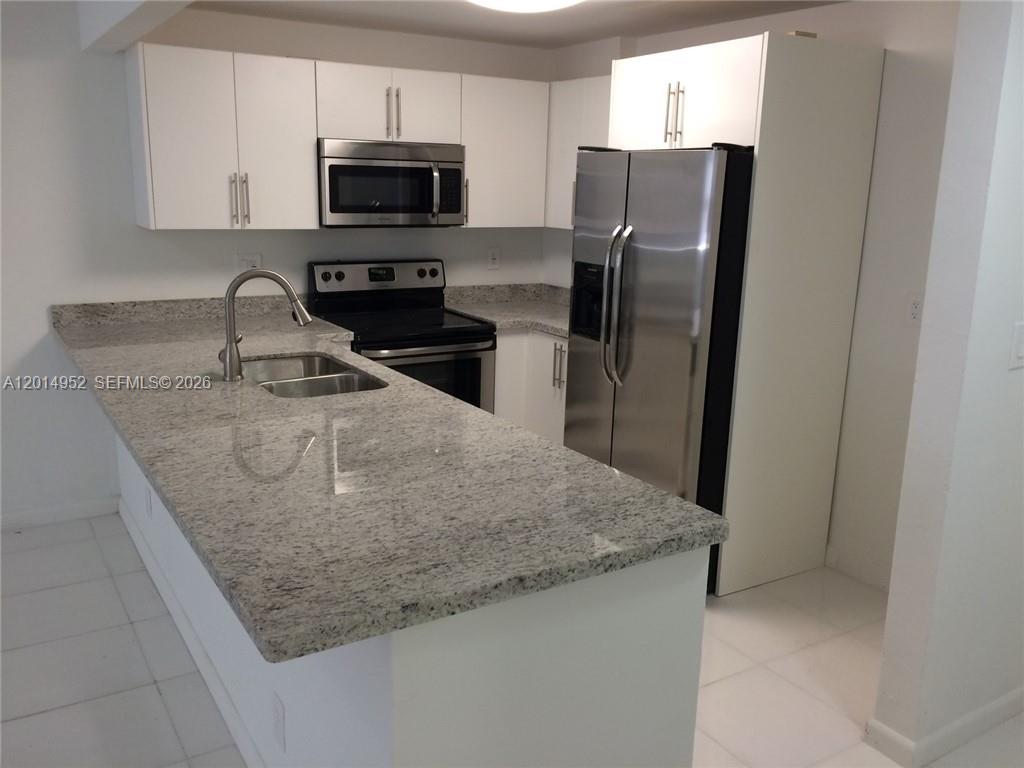 A kitchen features white cabinets, stainless steel appliances, and a light-colored granite countertop — 9143 SW 77 AV # B107, Miami FL 33156, MIAMI, FL