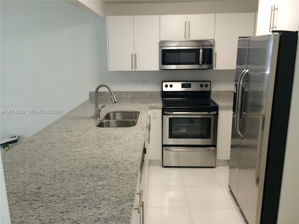 A kitchen features white cabinets, stainless steel appliances, and speckled granite countertops — 9143 SW 77 AV # B107, Miami FL 33156, MIAMI, FL