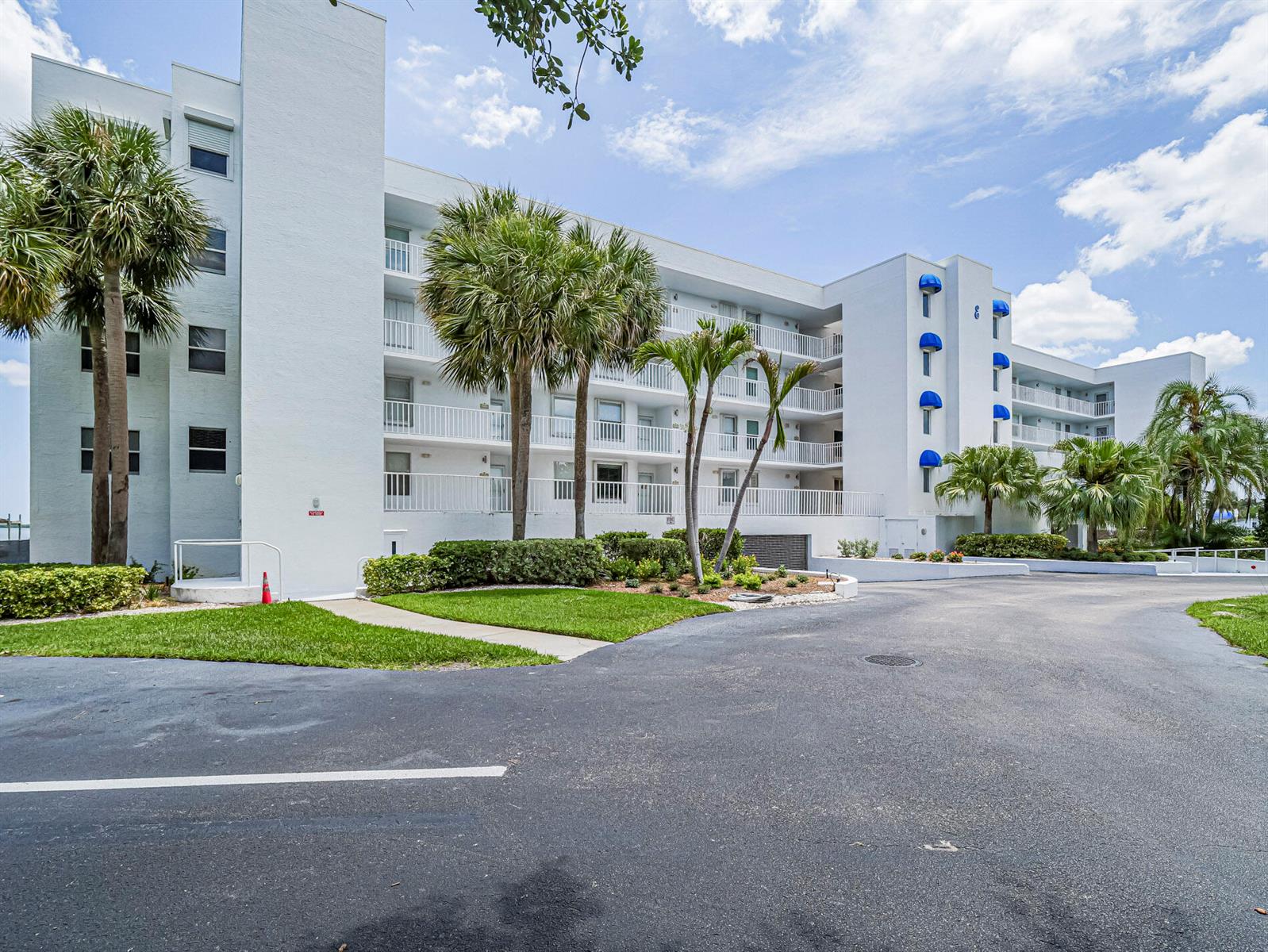 A multi-story white apartment building features balconies, palm trees, and a paved parking lot — 6005 River Run Drive, Sebastian FL 32958, SEBASTIAN, FL