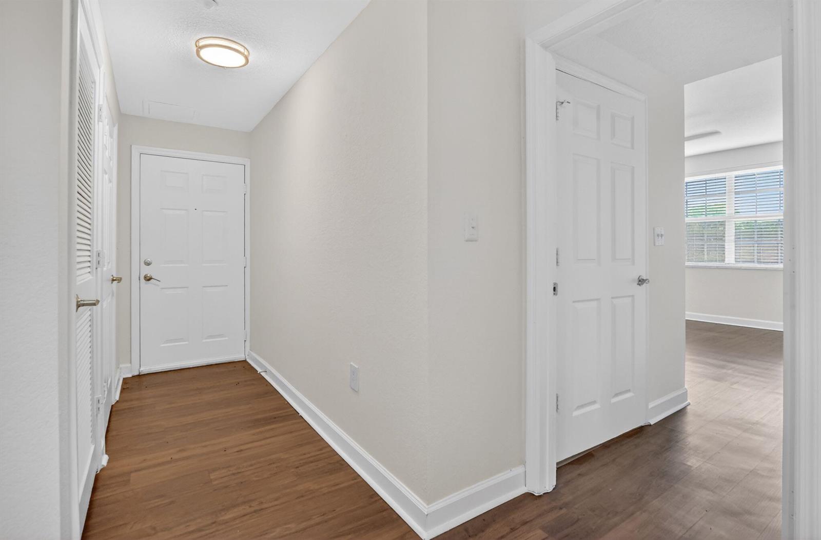 An entryway with wood-look flooring, white walls, and two closed white interior doors — 15085 Michelangelo Boulevard # 108, Delray Beach FL 33446, DELRAY BEACH, FL