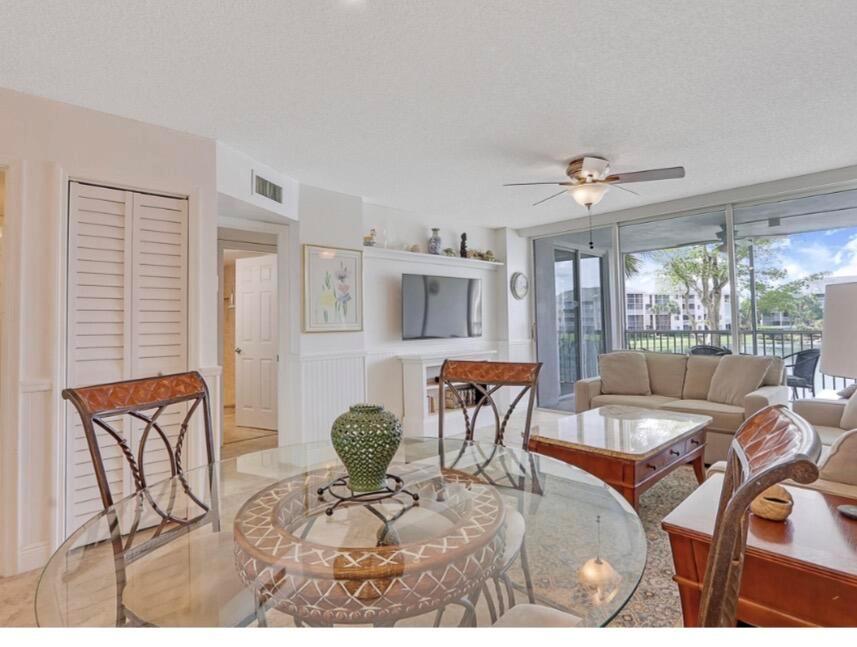 A dining area with a glass table overlooks a living room with a balcony view — 353 S Us Highway 1 # A207, Jupiter FL 33477, JUPITER, FL