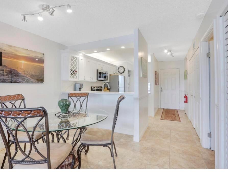 A dining area with a glass table leads into a kitchen with white cabinetry — 353 S Us Highway 1 # A207, Jupiter FL 33477, JUPITER, FL