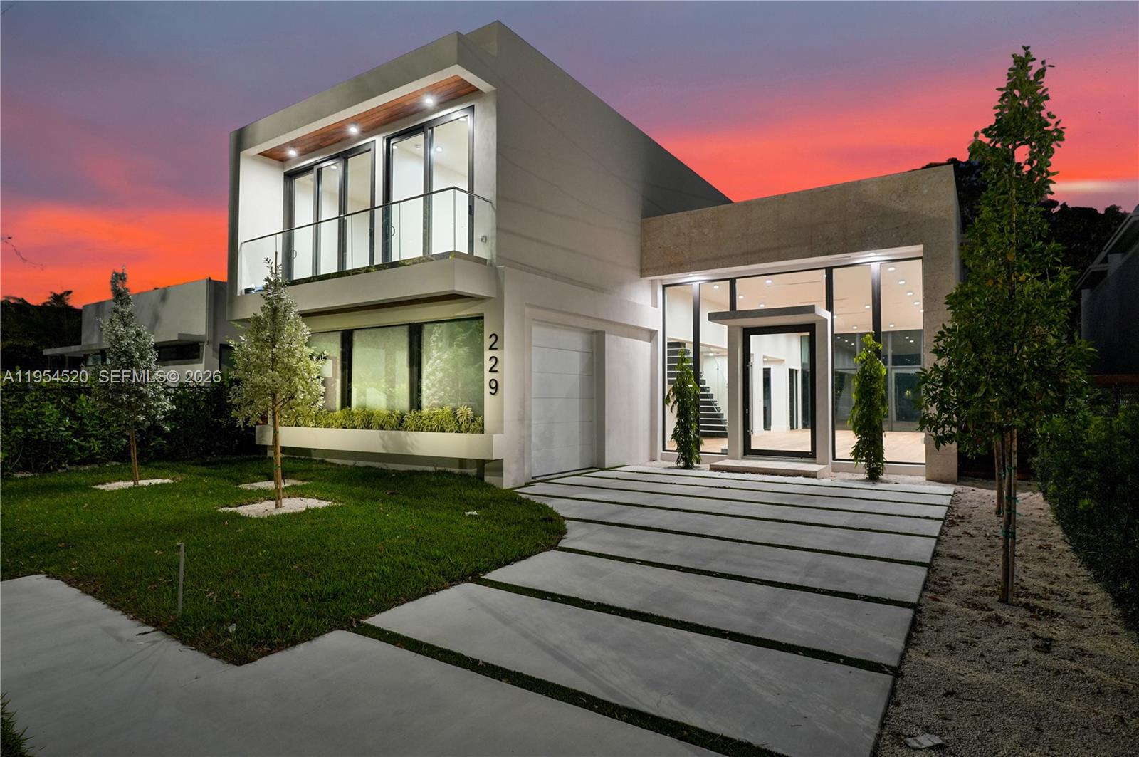 A modern two-story house features a concrete driveway, glass balcony, and large floor-to-ceiling windows — 229 NW 42nd St, Miami FL 33127, MIAMI, FL