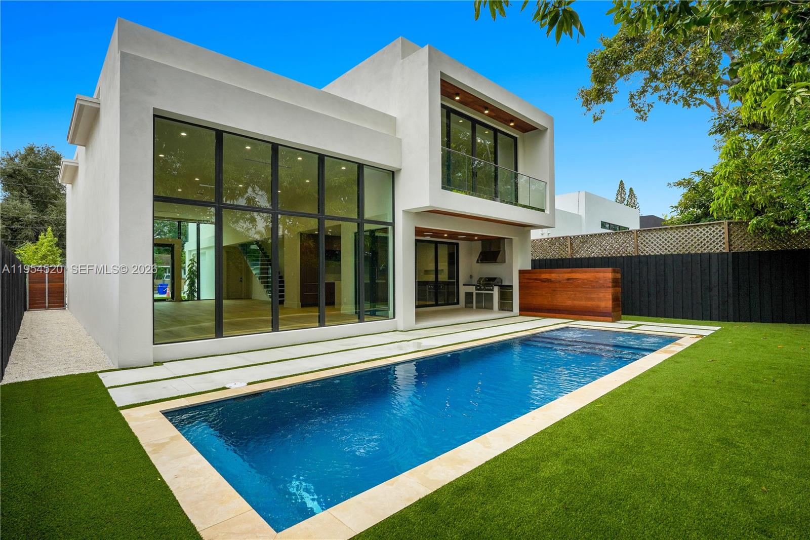 A modern two-story white house features a rectangular swimming pool and a grassy backyard — 229 NW 42nd St, Miami FL 33127, MIAMI, FL