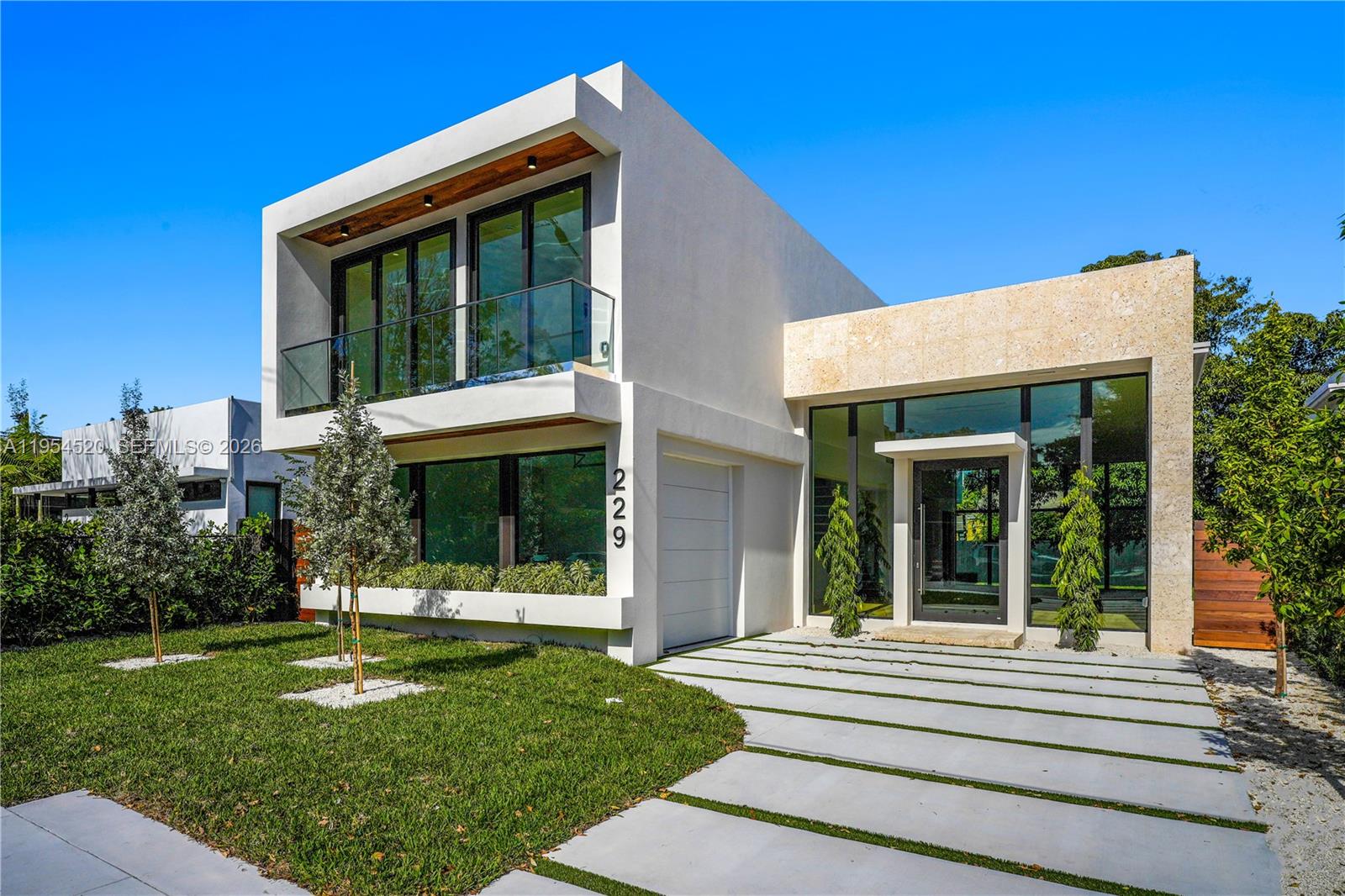 A modern two-story house features a white stucco facade, stone accents, and a glass balcony — 229 NW 42nd St, Miami FL 33127, MIAMI, FL