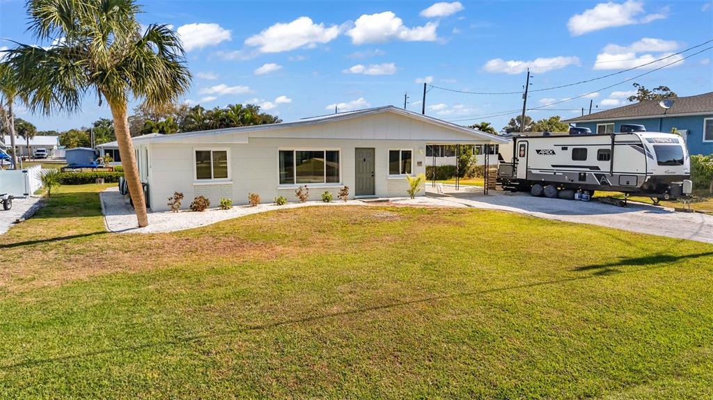 A single-story house with a carport and a parked travel trailer on a grassy lot — 1495 S MARYKNOLL ROAD, ENGLEWOOD, FL