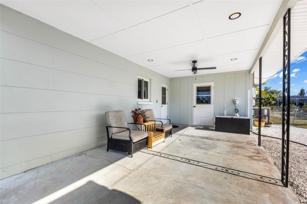 A covered concrete patio features a ceiling fan, recessed lighting, and a small seating area — 1495 S MARYKNOLL ROAD, ENGLEWOOD, FL