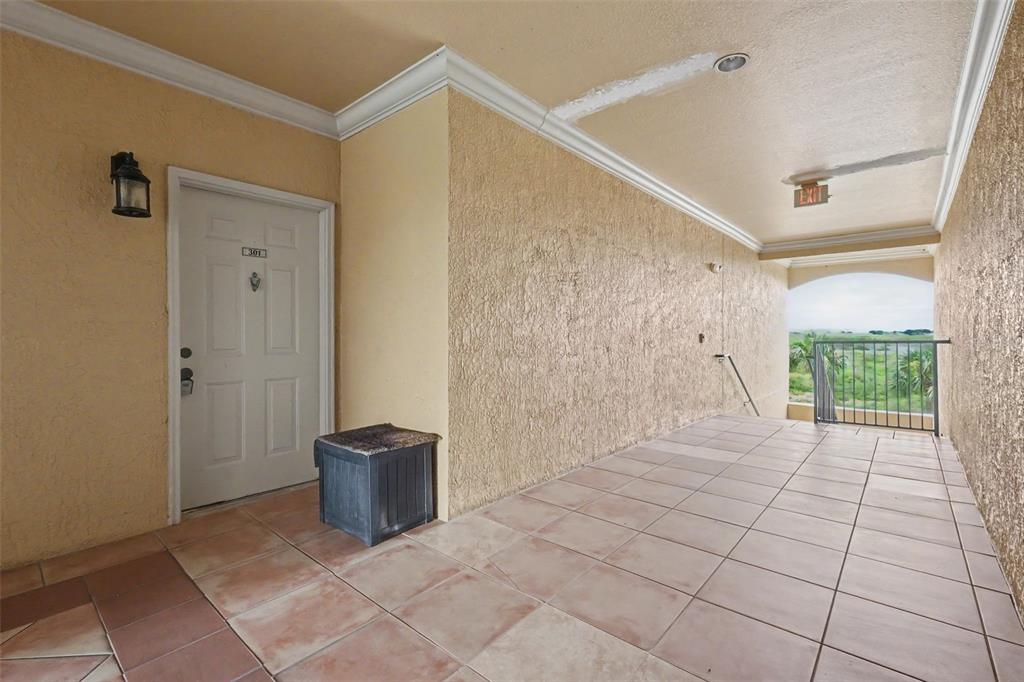 An exterior apartment hallway features a tiled floor, a white door, and a metal railing — 4306 BAYSIDE VILLAGE DRIVE UNIT 301, TAMPA, FL