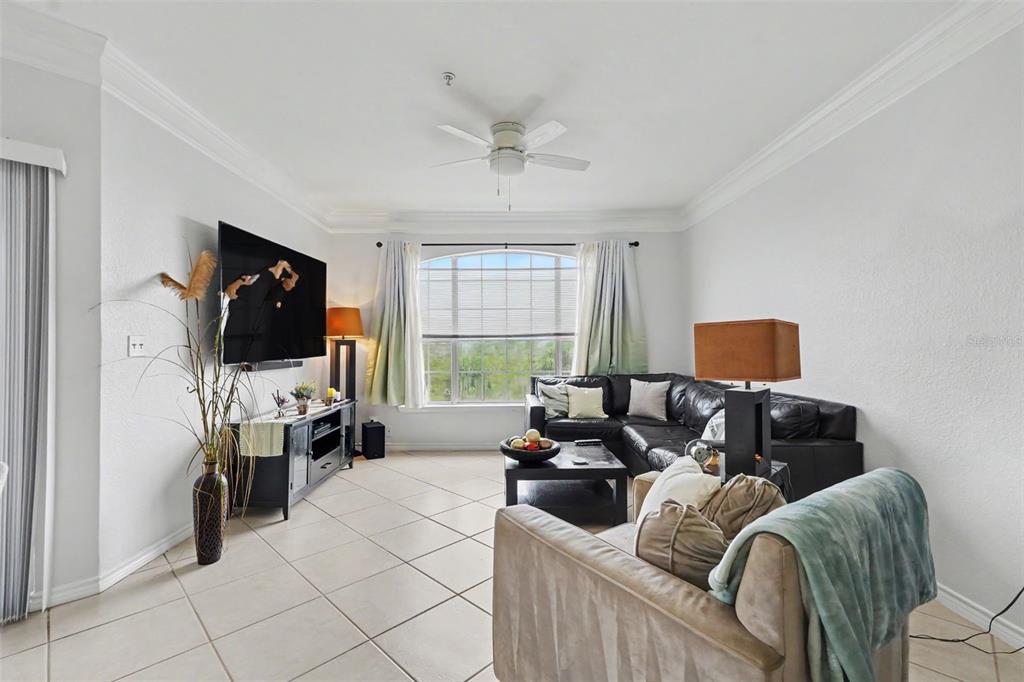 A living room features a black sectional sofa, a television, and tile flooring — 4306 BAYSIDE VILLAGE DRIVE UNIT 301, TAMPA, FL