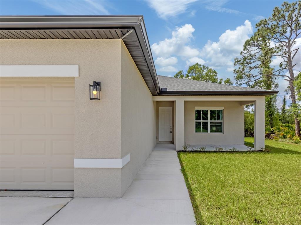 A beige house exterior features a garage, a front porch, and a concrete walkway — 1047 COMFORT LANE, NORTH PORT, FL