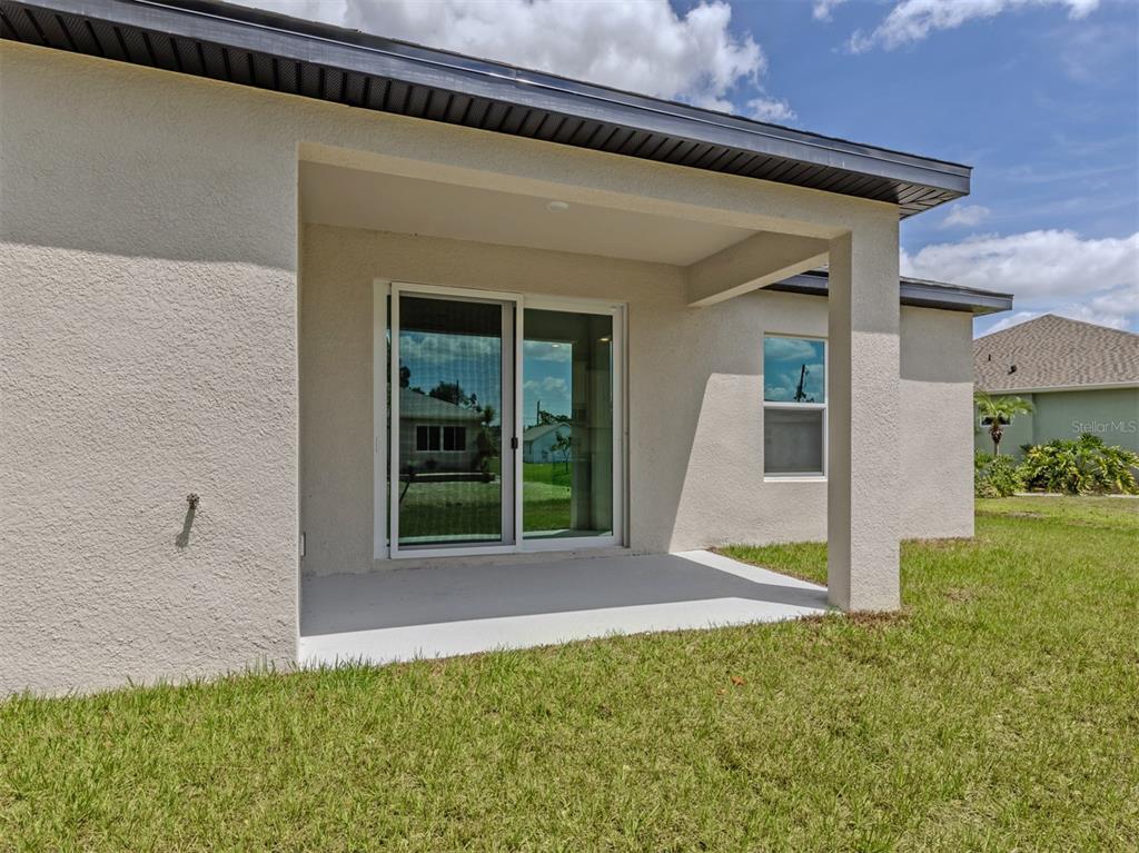 A covered concrete patio features a sliding glass door and a single window — 1047 COMFORT LANE, NORTH PORT, FL