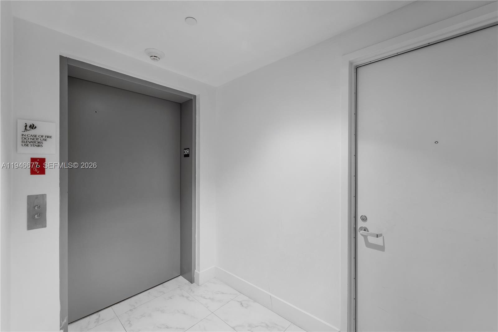 A hallway features a gray elevator door, a white door, and white tiled flooring — 460 NE 28th St # 3002, Miami FL 33137, MIAMI, FL
