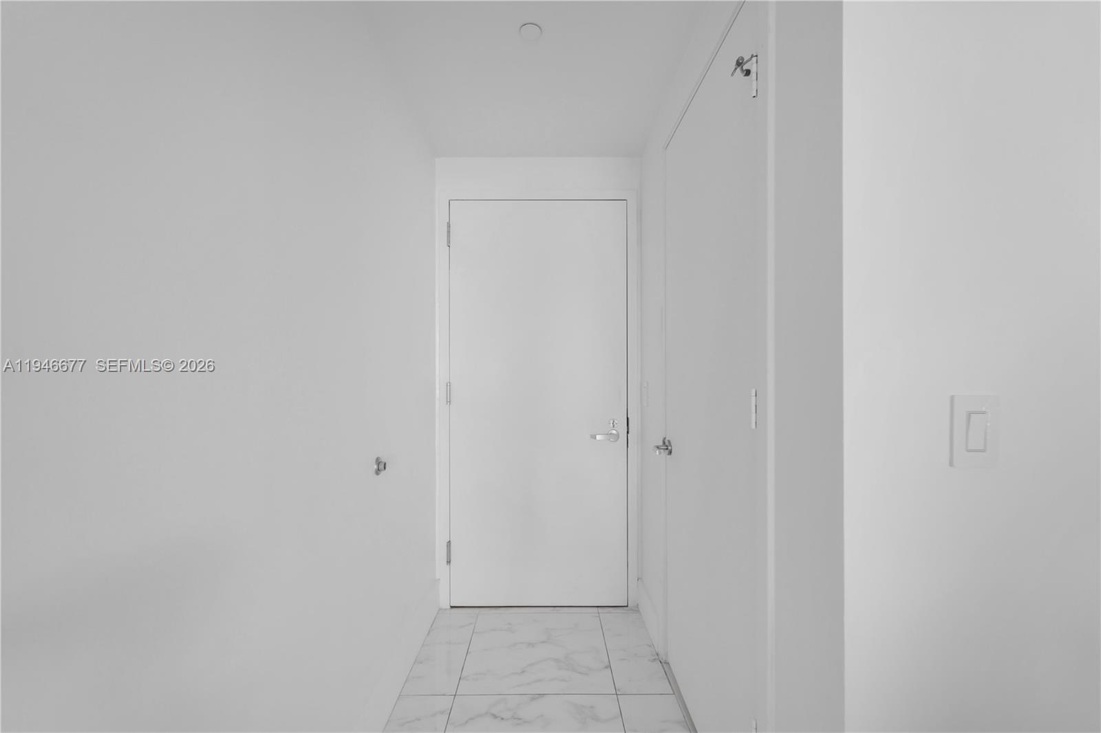 A narrow hallway features white walls, a white door, and light-colored marble-patterned tile flooring — 460 NE 28th St # 3002, Miami FL 33137, MIAMI, FL
