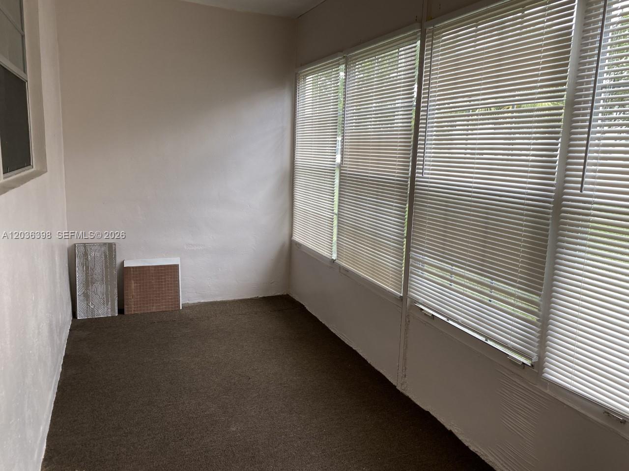 A sunroom with brown carpeting, white walls, and large windows covered by horizontal blinds — 6507 Winfield Blvd # C, Margate FL 33063, MARGATE, FL
